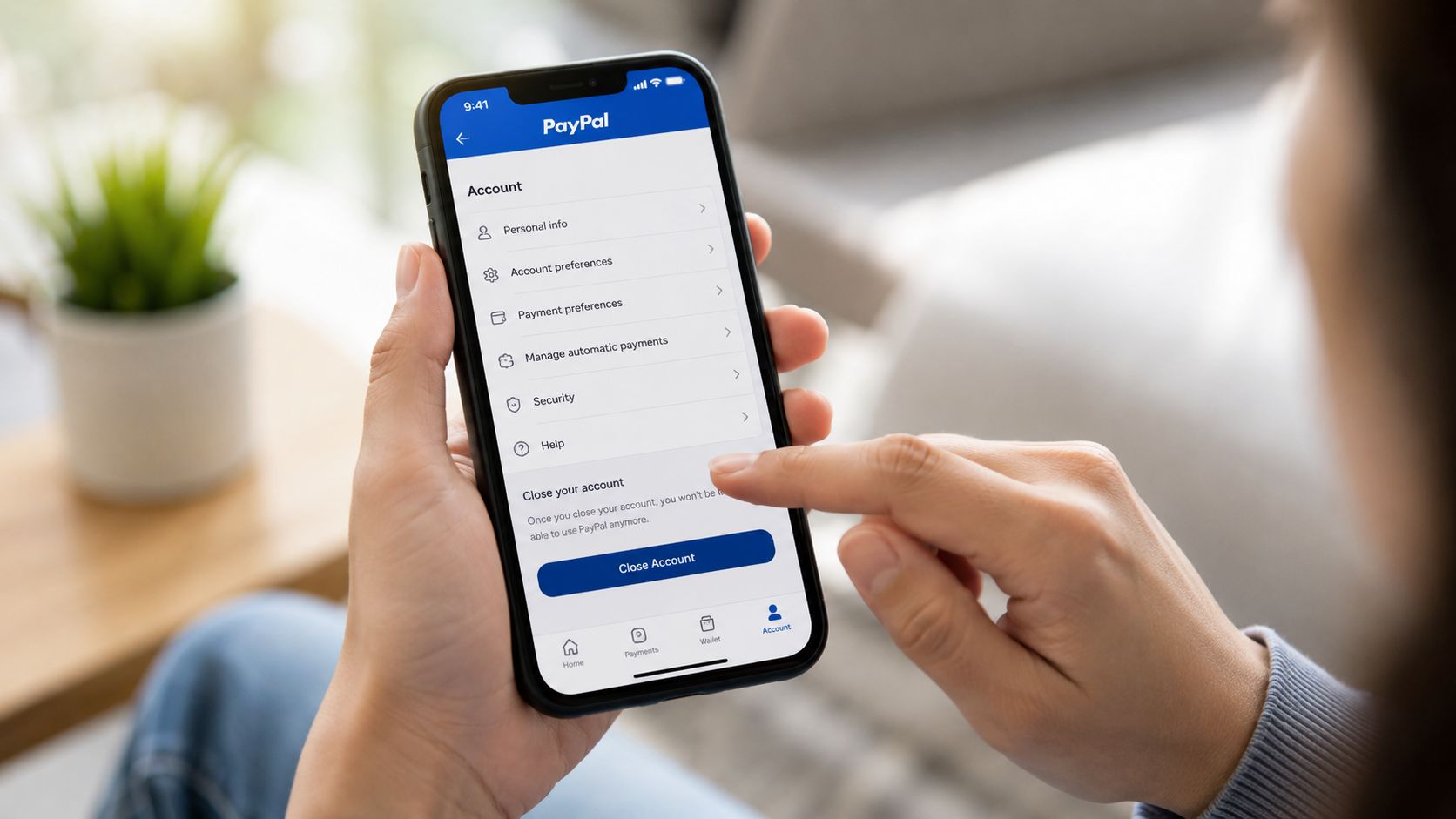 A person holding a smartphone and navigating the PayPal account settings menu to close their account.