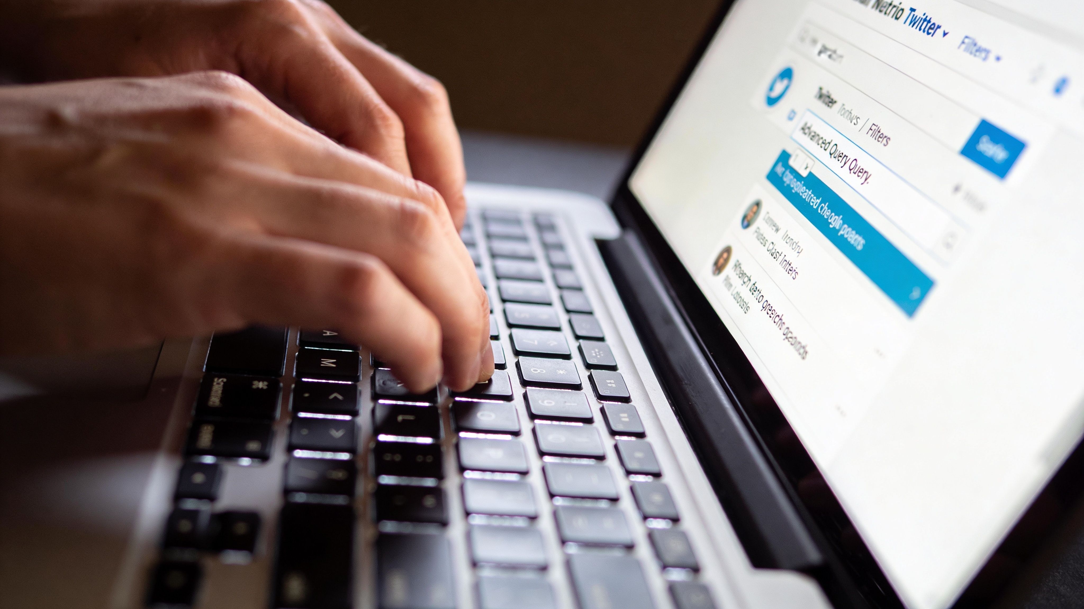 A close-up view of a person using a laptop to navigate the Twitter search interface.