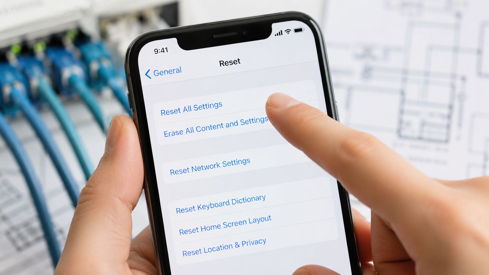 A person holding a smartphone and selecting the reset settings option on the iOS device screen.
