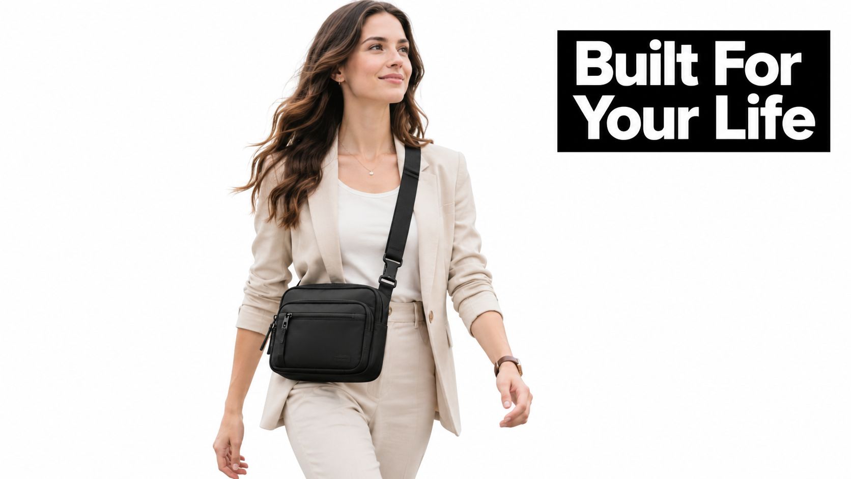 A professional woman walking confidently while wearing a black crossbody work bag against a white background.