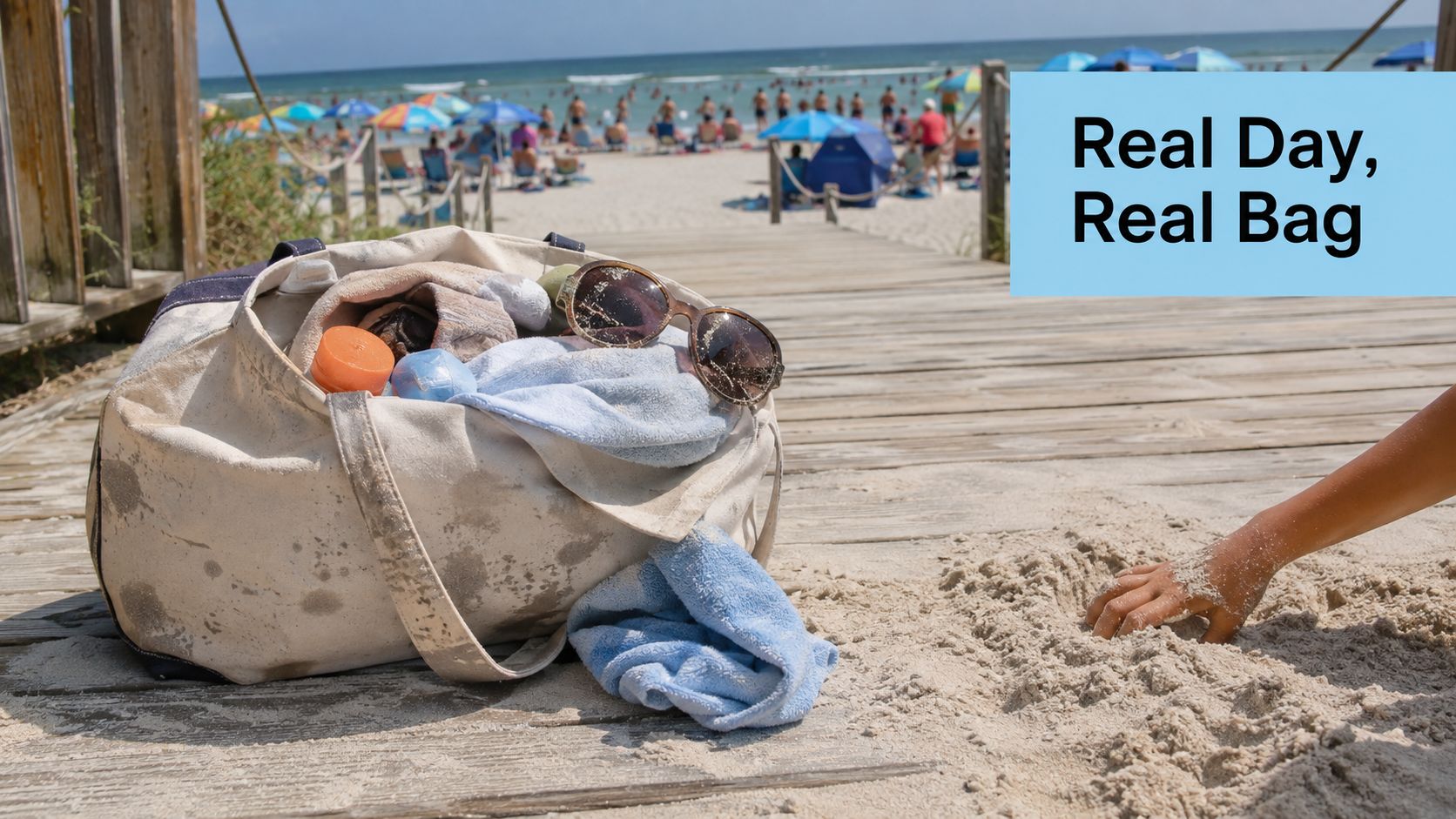 A canvas beach bag filled with towels and sunglasses sitting on a wooden walkway near the beach.