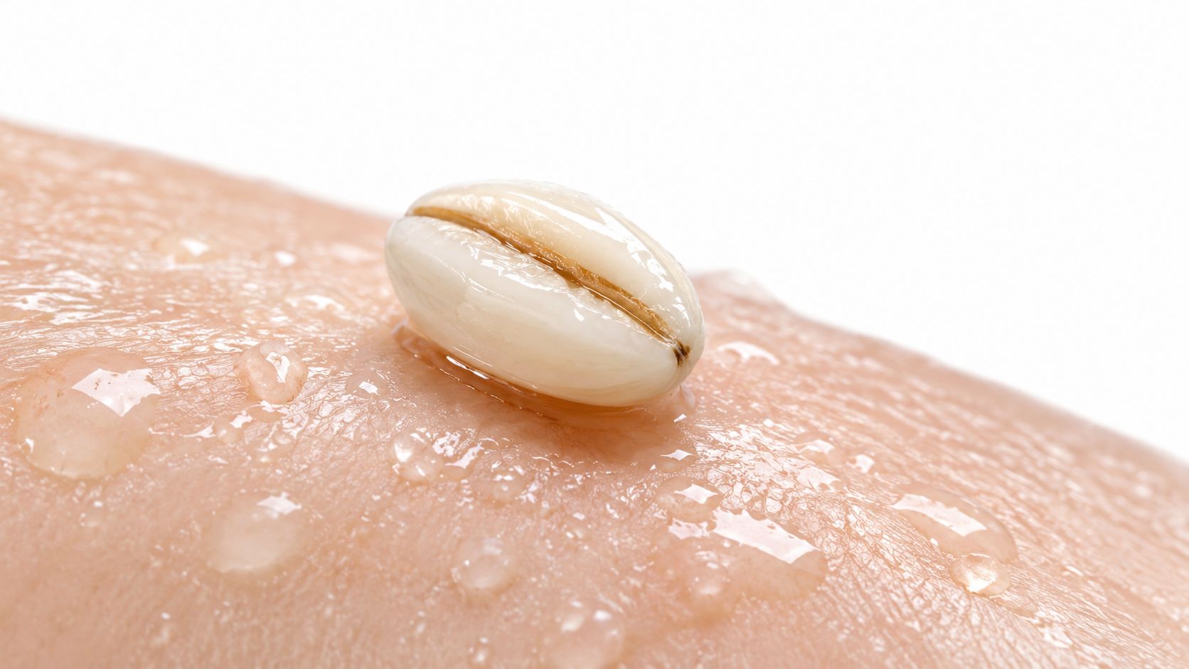 A single pearl barley grain resting on skin covered with refreshing water droplets, symbolizing hydration benefits.