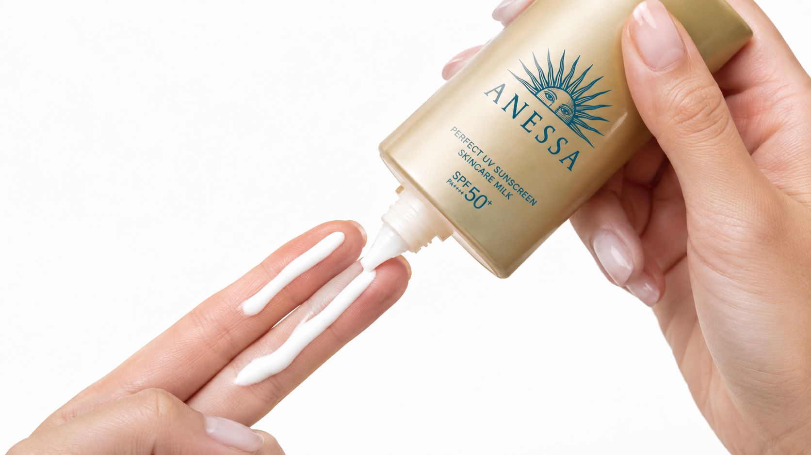 En person, der klemmer hvid Anessa Perfect UV Sunscreen Skincare Milk ud på fingrene foran en hvid baggrund.