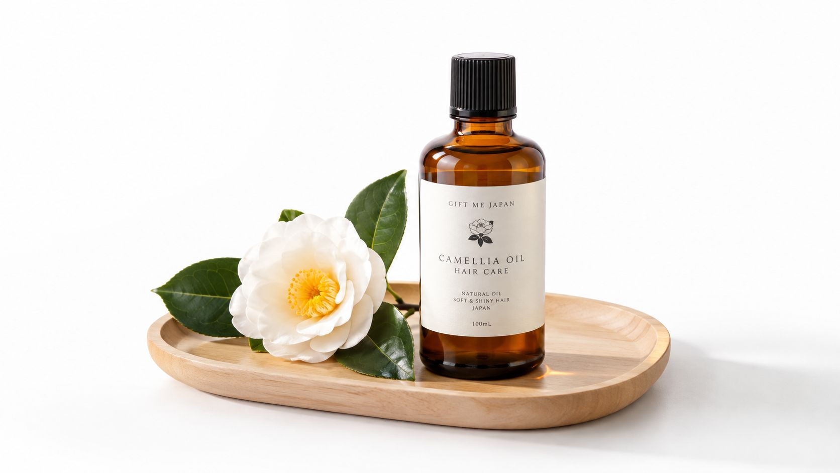 A glass bottle of Japanese camellia oil for hair care placed on a wooden tray with a flower.