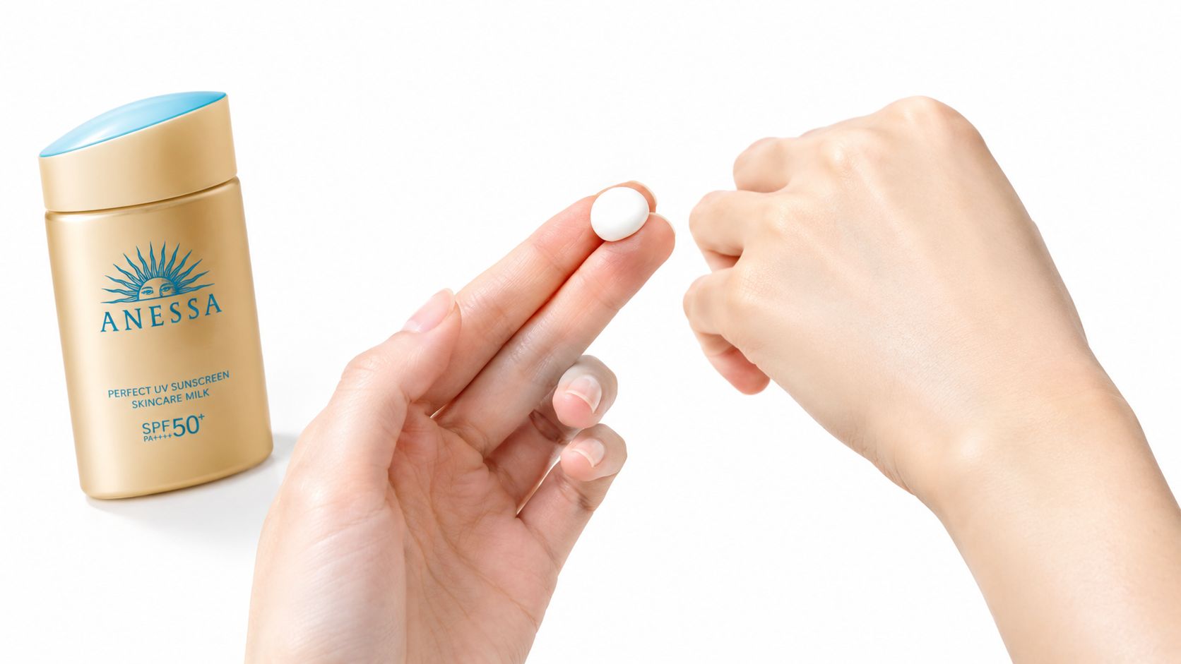 A hand holding a dab of Anessa sunscreen next to an Anessa Perfect UV Sunscreen Skincare Milk bottle.