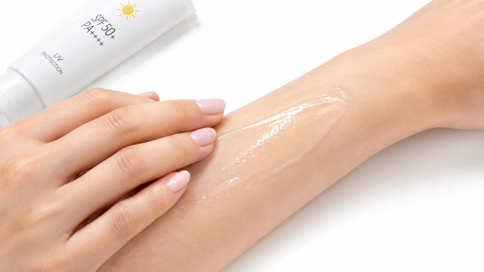 A close-up view of a person applying transparent Japanese sunscreen onto their forearm with a white tube