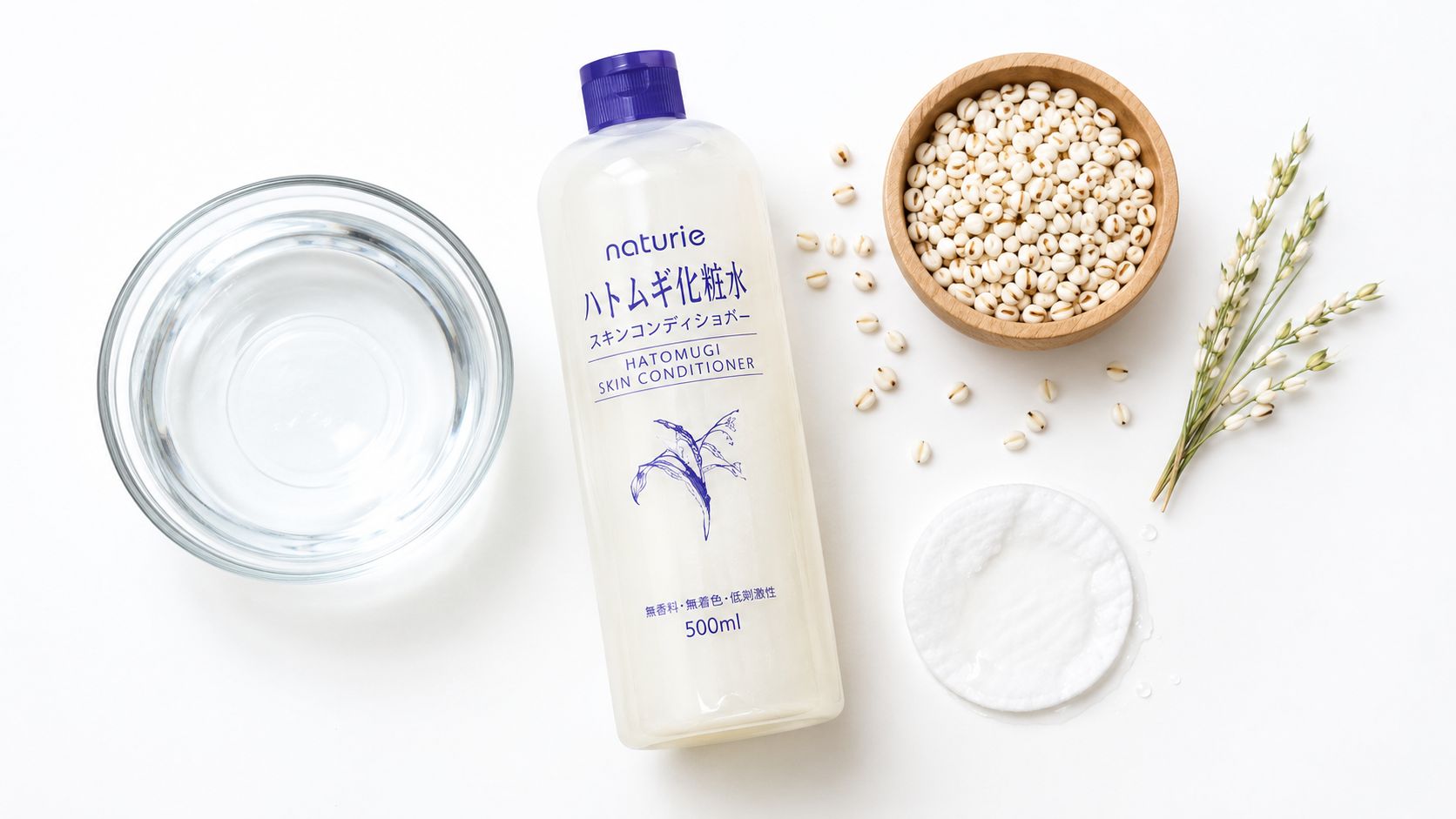 A bottle of Naturie Hatomugi Skin Conditioner, a bowl of Job's tears, water, and cotton pads.