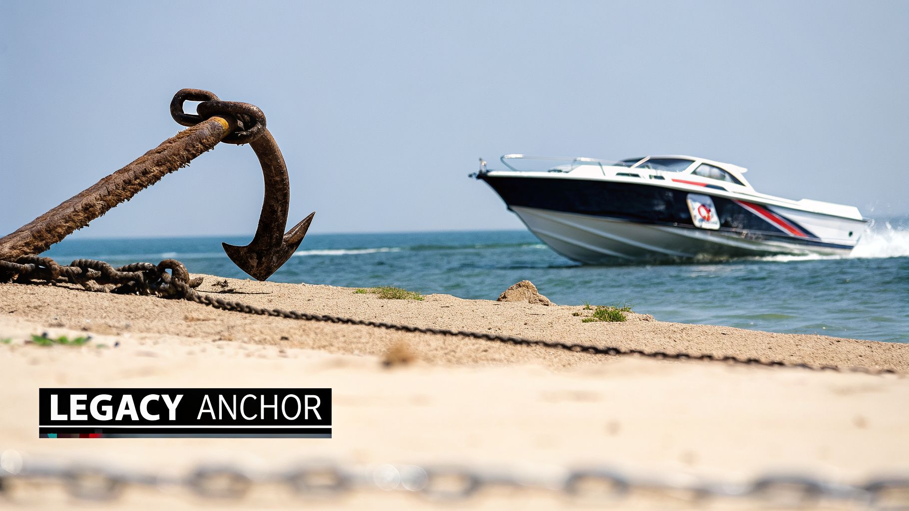 A large rusty anchor and chain rest on a sandy beach, with a speed boat cruising across the ocean.