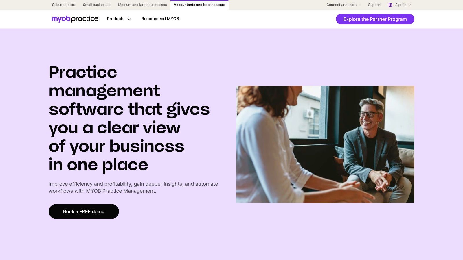 A business meeting with professionals discussing strategy around a laptop displaying MYOB Practice Management dashboards.
