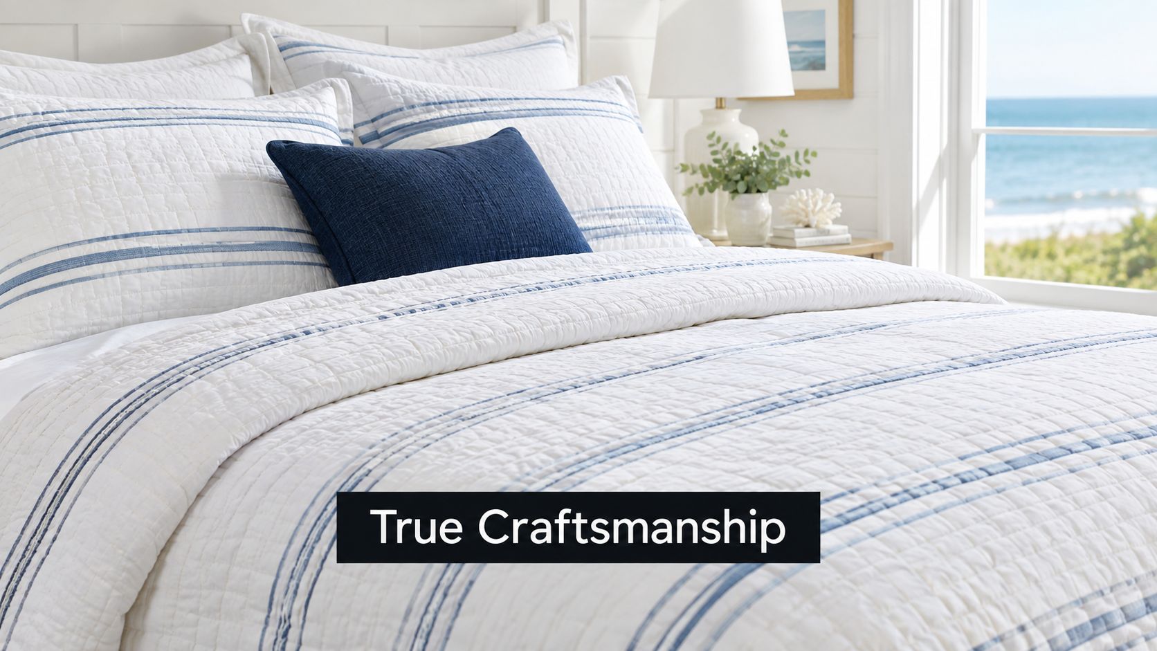 A cozy, coastal-themed bed with a white quilted coverlet featuring blue stripes and a decorative navy pillow.