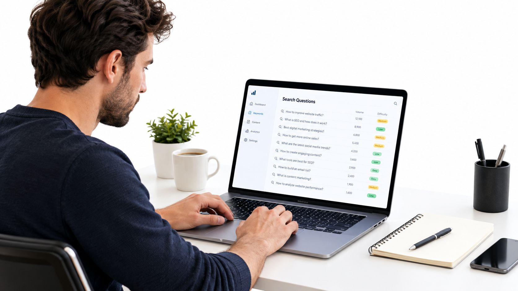 A man working on his laptop analyzing SEO search questions in a bright modern office setting.