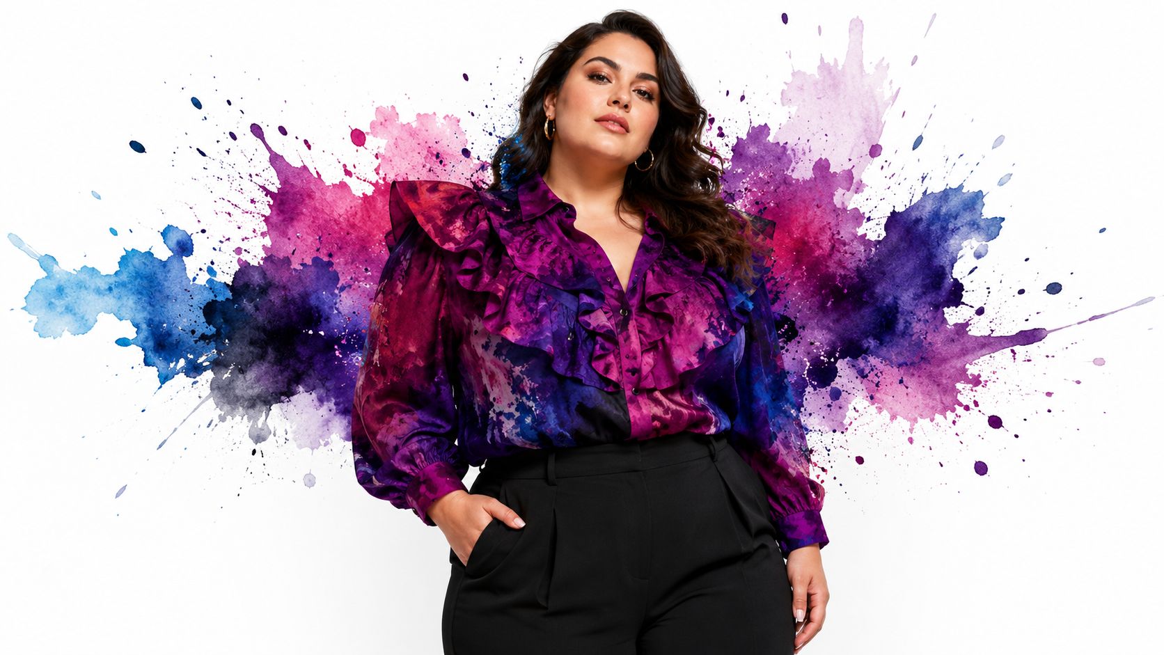 A curvy woman with long wavy hair wears a purple and pink ruffled blouse with black pants.