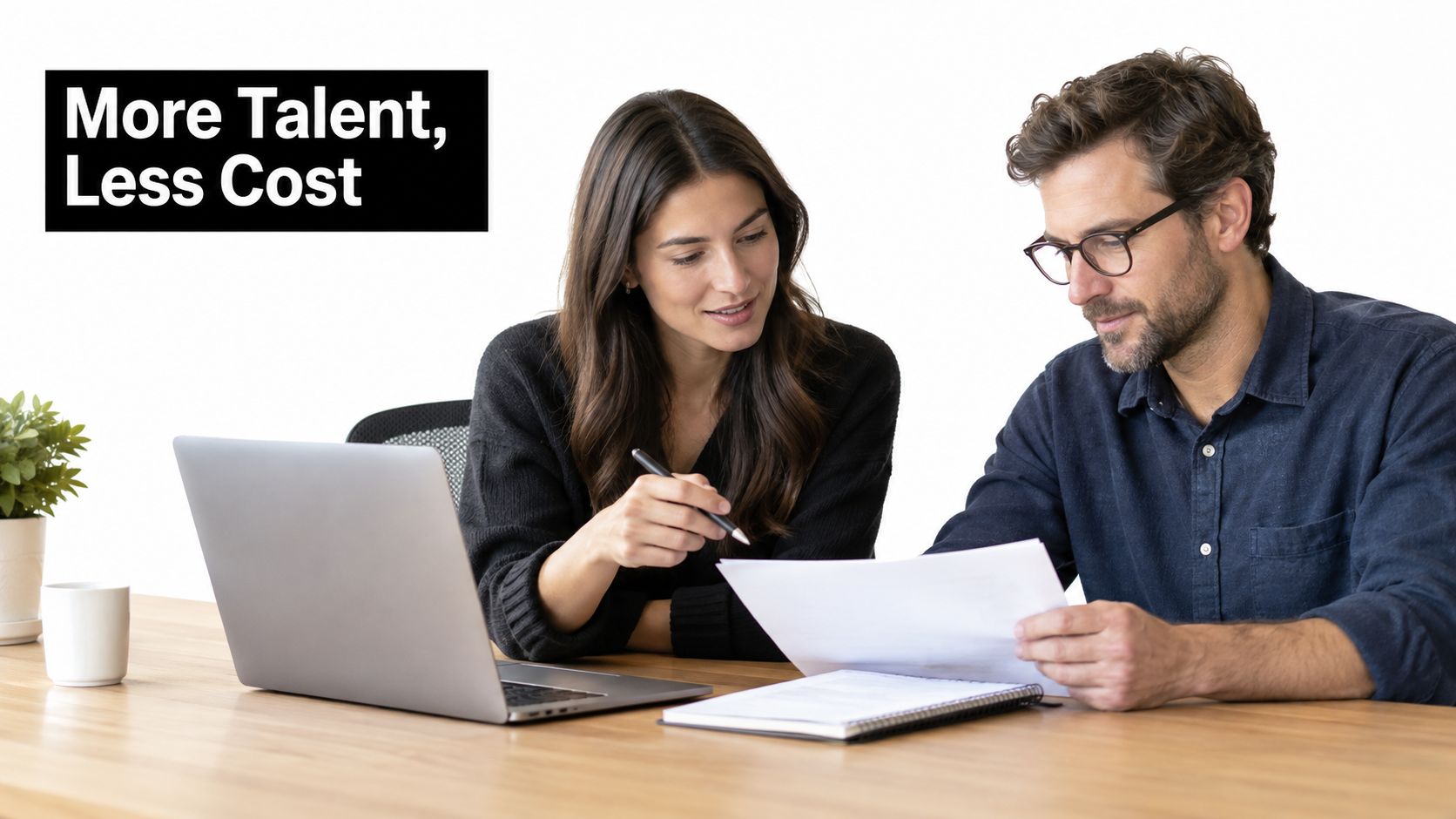 A professional woman and man collaborating on a project with a laptop and documents on a desk.