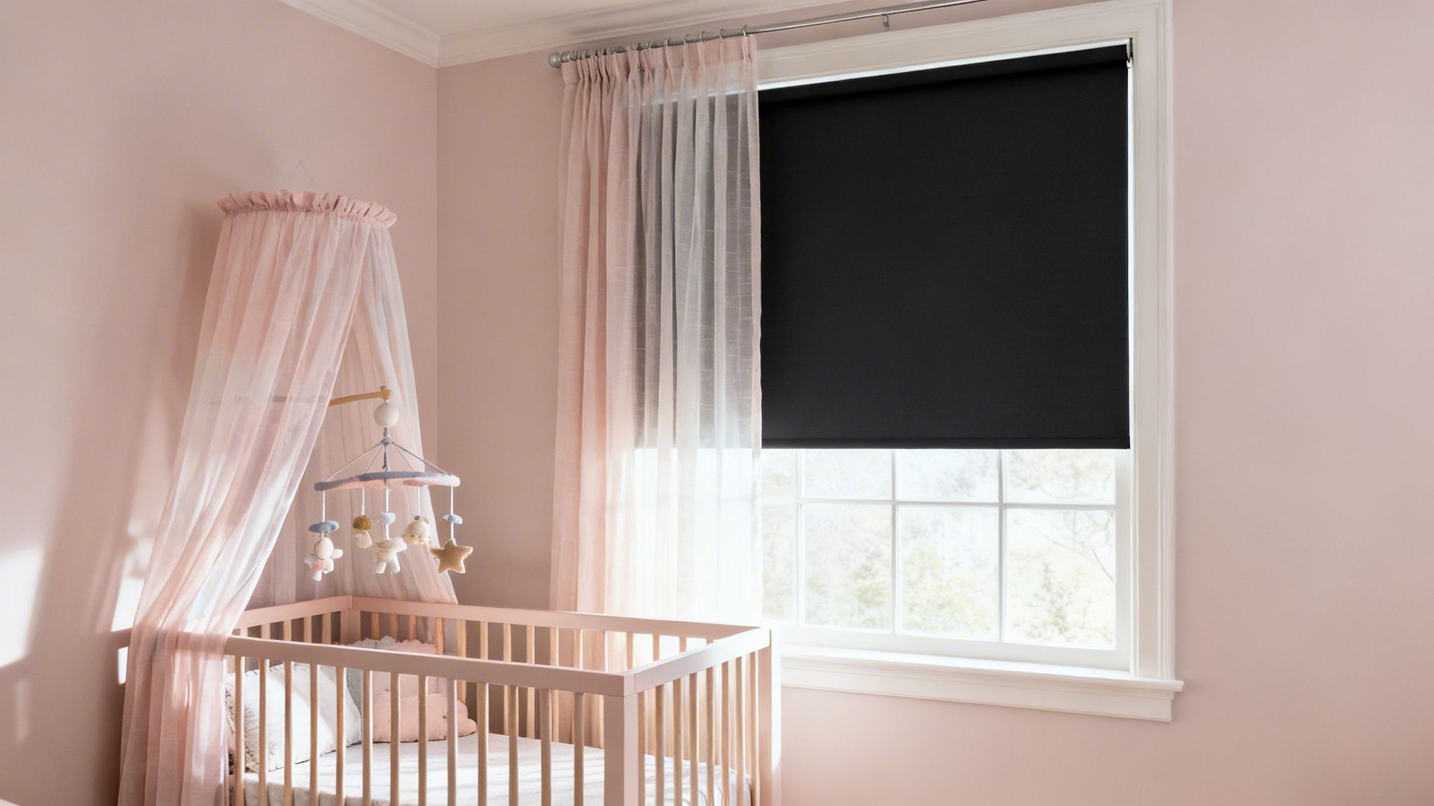 a baby's nursery with pink walls, crib, mobile, sheer curtains, and a black blackout shade.