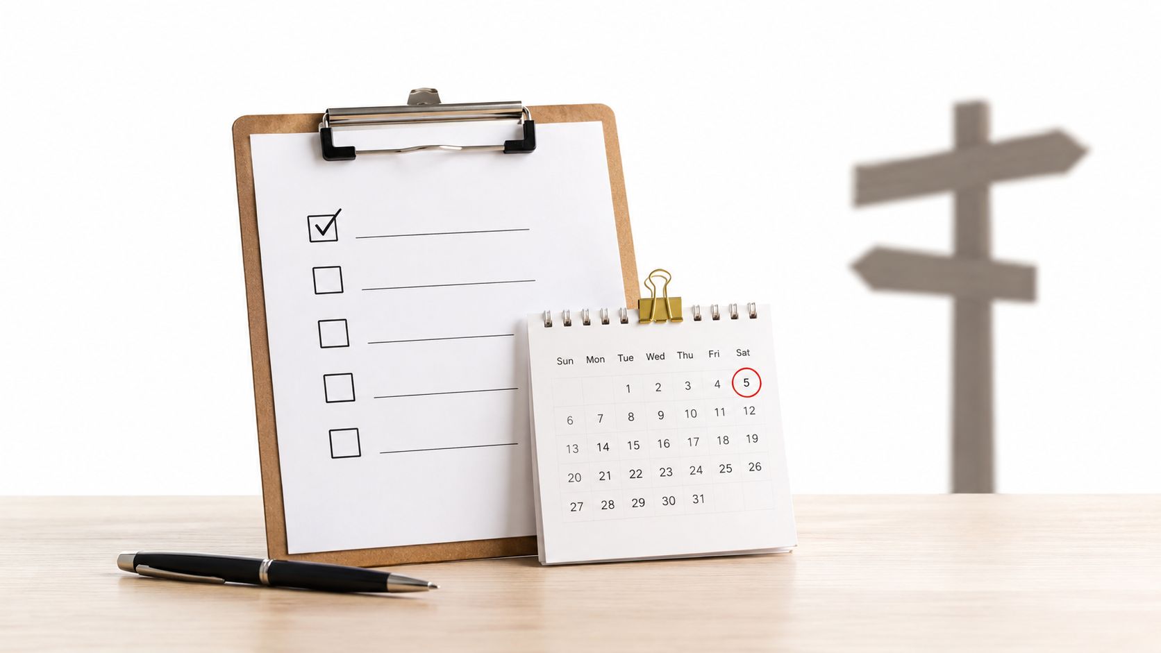 A clipboard with a checklist, a desk calendar with the fifth highlighted, and a pen on a desk.