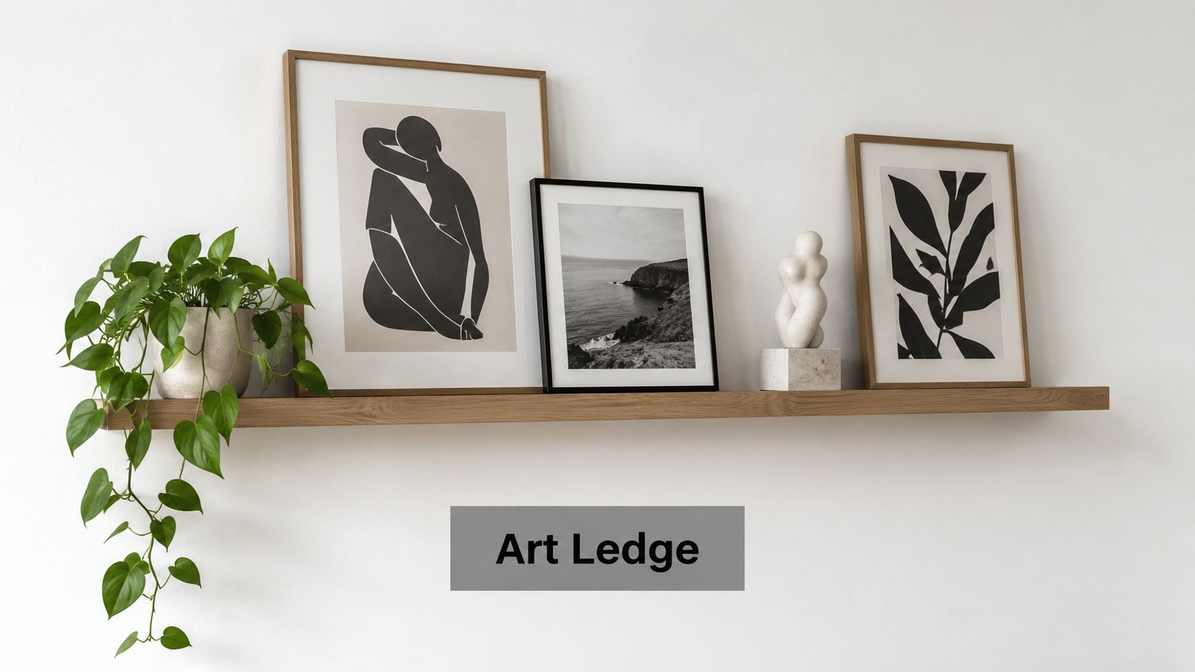 A wooden art ledge shelf displays modern black and white framed prints and a sculptural decorative object.
