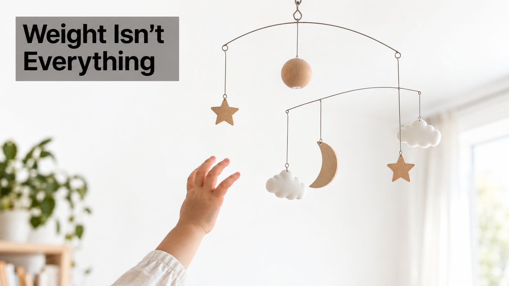 A baby's hand reaching up towards a decorative wooden hanging sculpture featuring stars, clouds, and a moon.