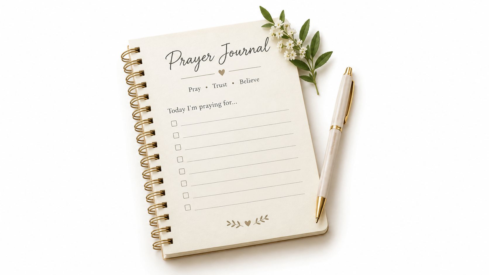 A spiral-bound prayer journal with an elegant pen and a small sprig of white flowers nearby.