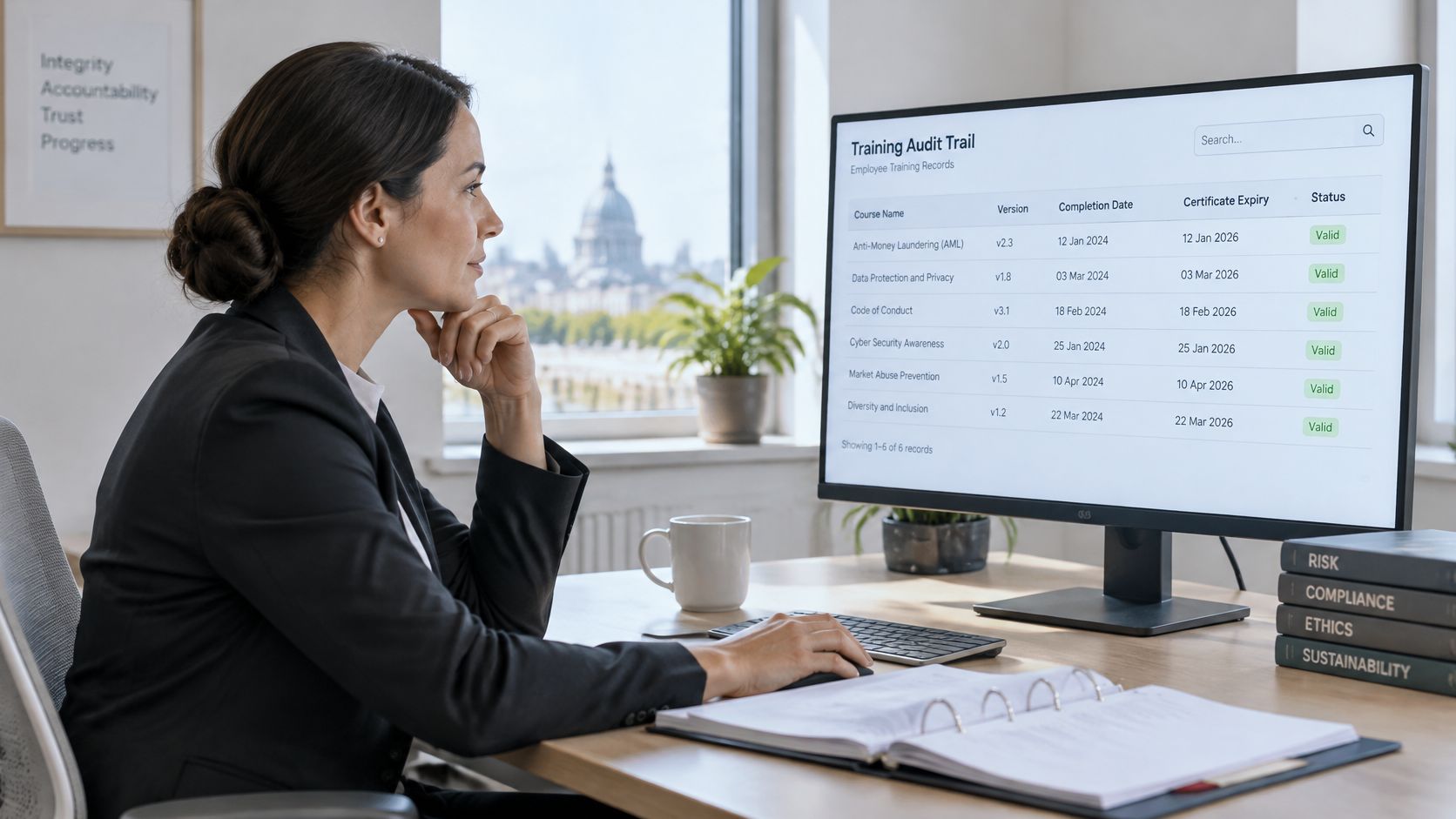 A professional woman reviewing her digital employee training audit trail on a computer screen in an office.