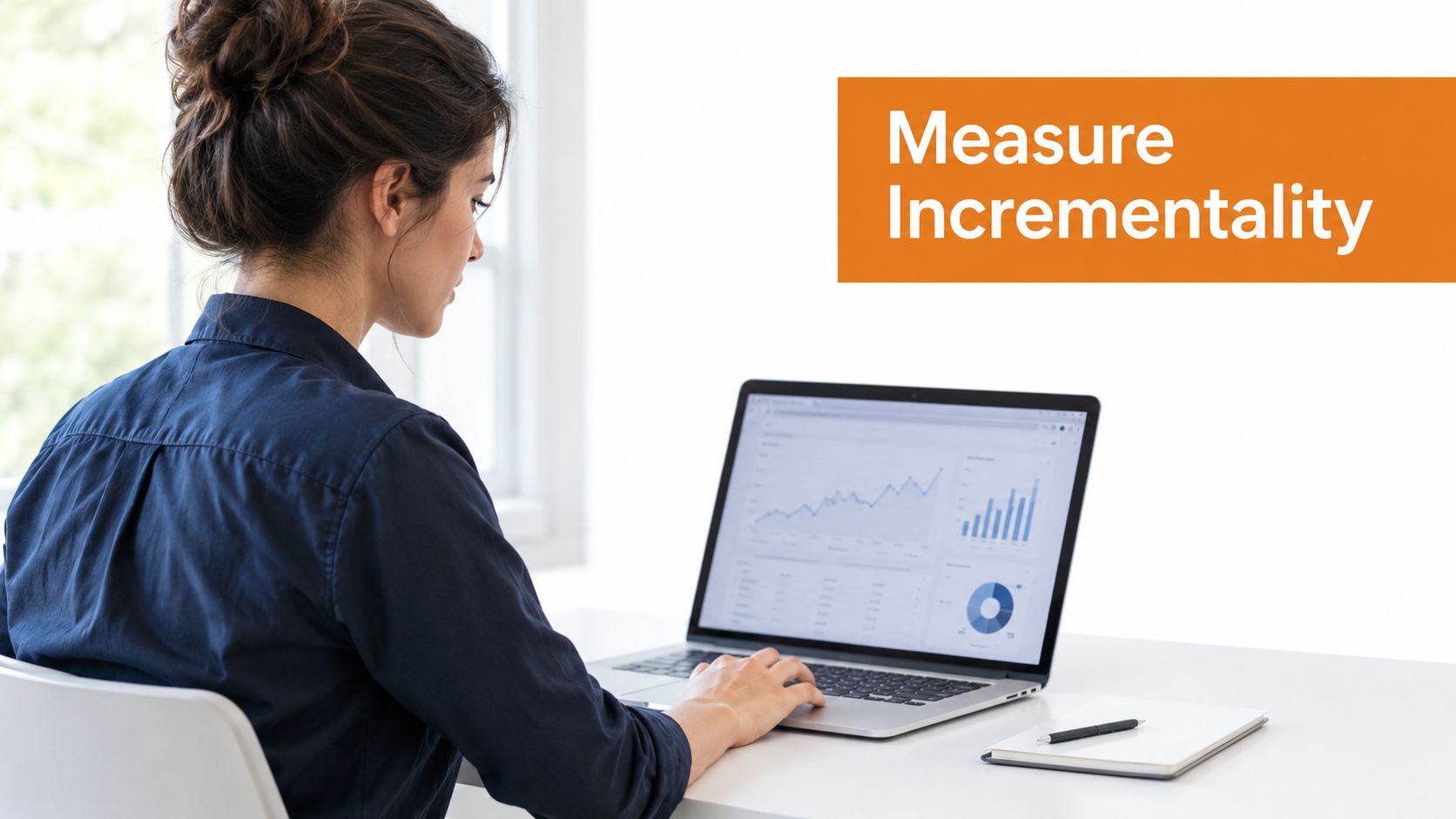 A woman working on a laptop with data visualizations, focused on measuring marketing incrementality and advertising performance.