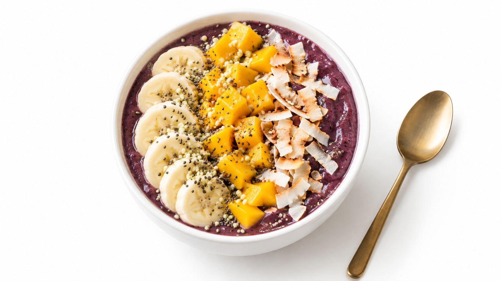 A healthy acai bowl topped with sliced bananas, fresh mango chunks, toasted coconut flakes, and chia seeds.