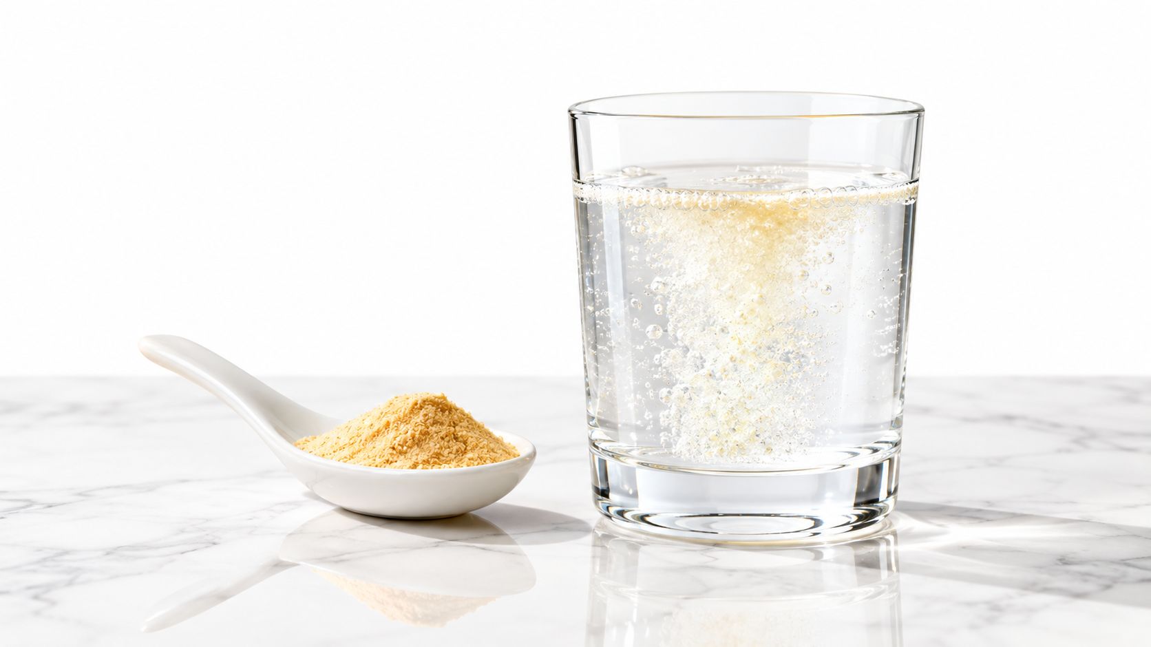 A spoonful of yellow nutritional powder next to a glass of water with effervescent bubbles.