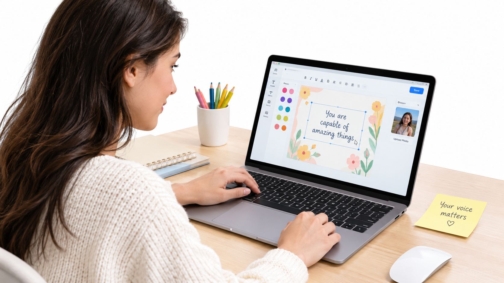 A female student using a laptop to edit a graphic design with inspirational text at her desk.