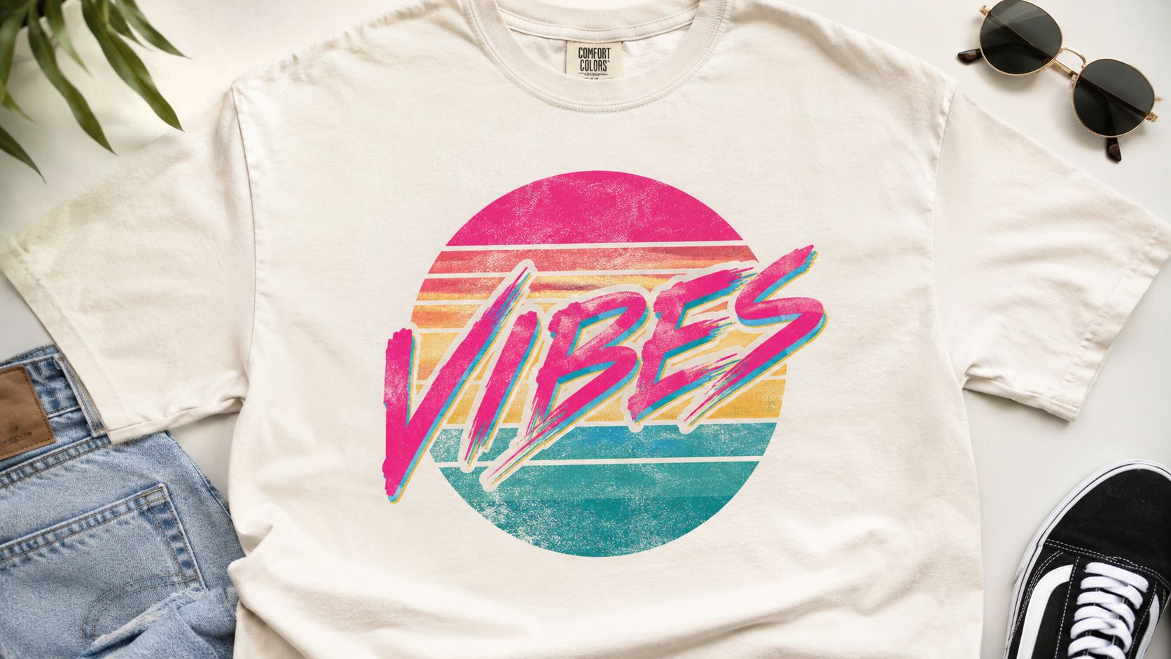 A beige graphic t-shirt featuring a retro 80s style circle design with the word VIBES printed across.