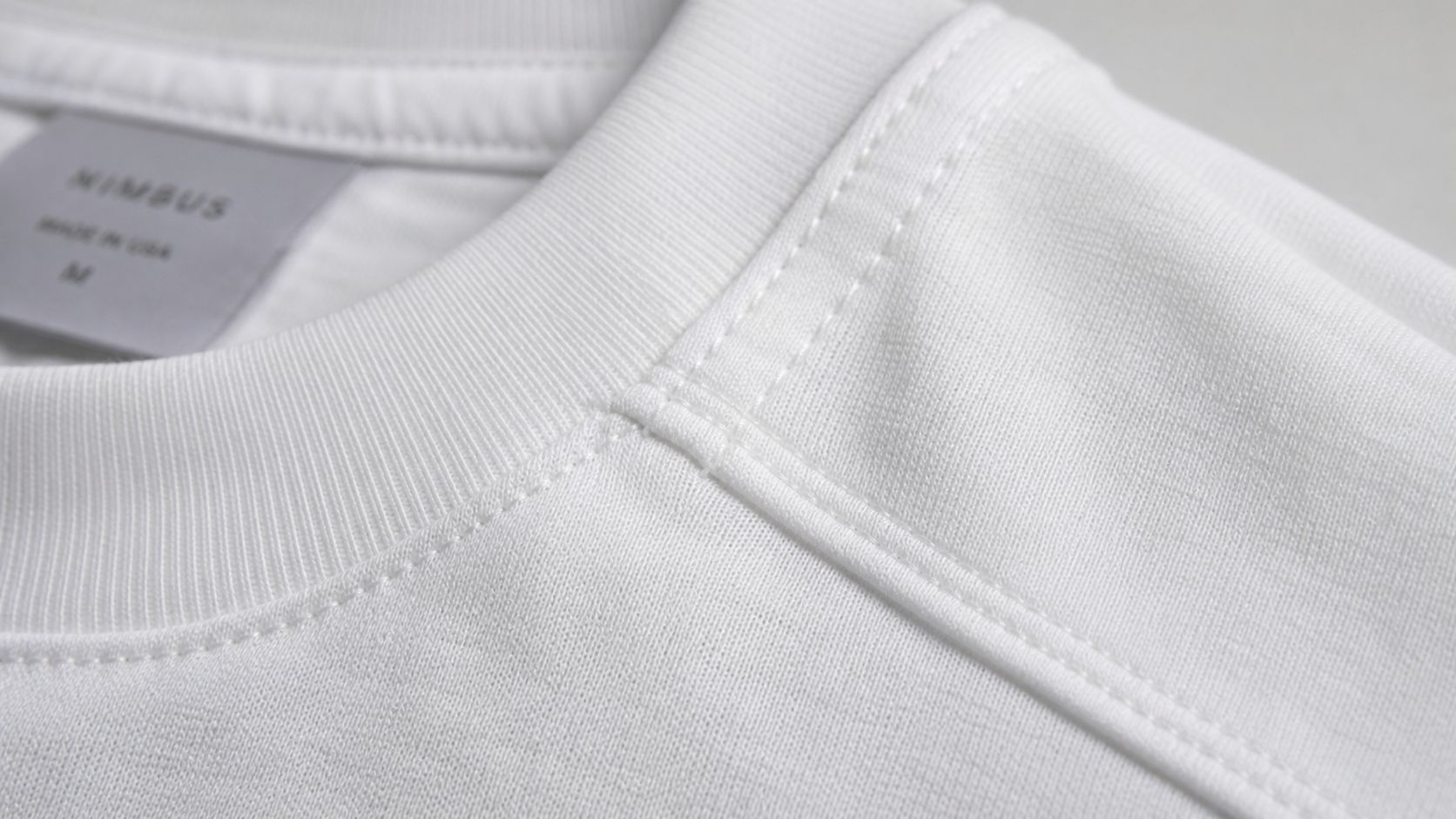 Close-up of a high-quality white t-shirt collar featuring reinforced stitching and a branded Nimbus label.