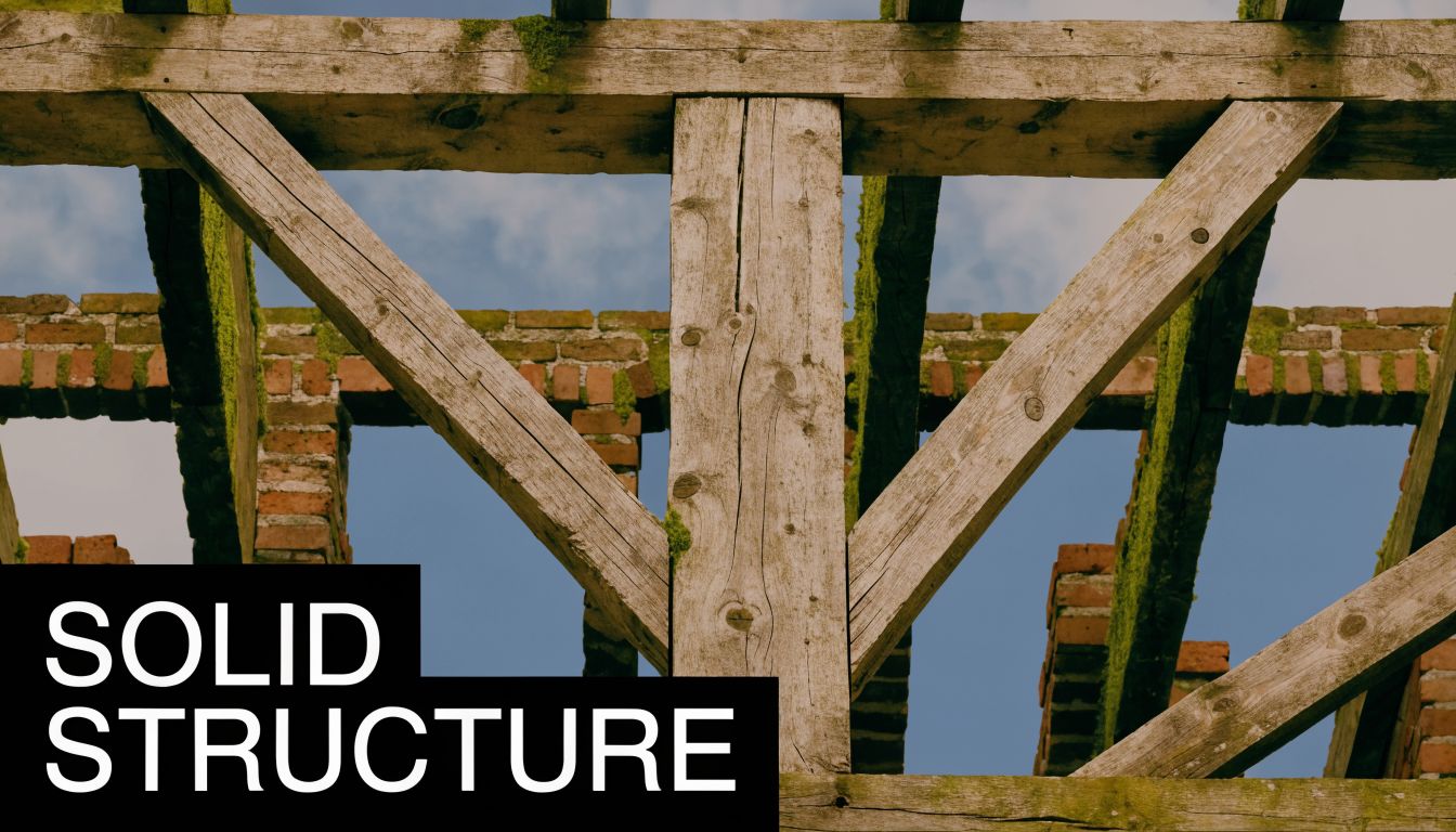 The weathered wooden roof beams of an old brick building against a blue sky background.
