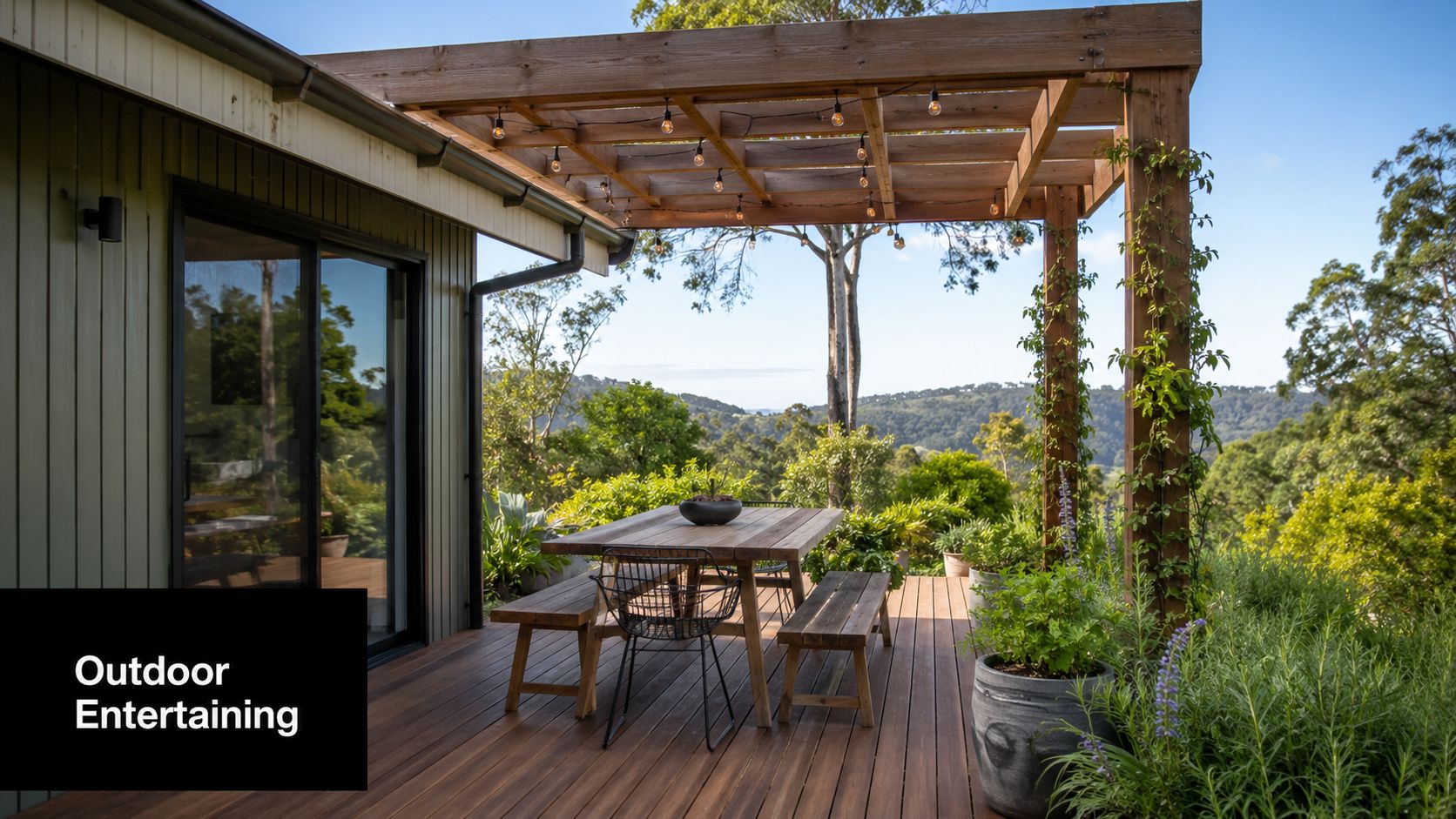 A wooden deck with a dining table and benches under a pergola overlooking rolling hills.
