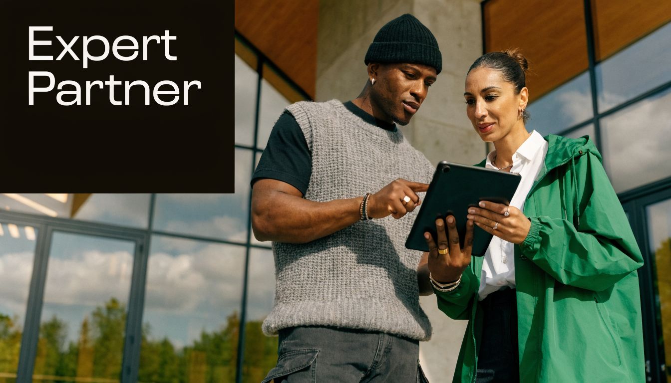 A professional man and woman discussing a project on a digital tablet in front of a building.