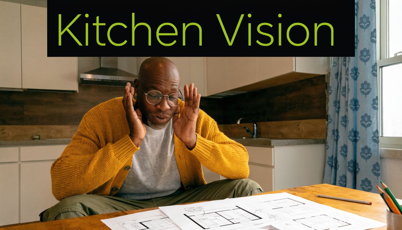 A man wearing glasses and a yellow cardigan sitting at a table with kitchen renovation blueprints.