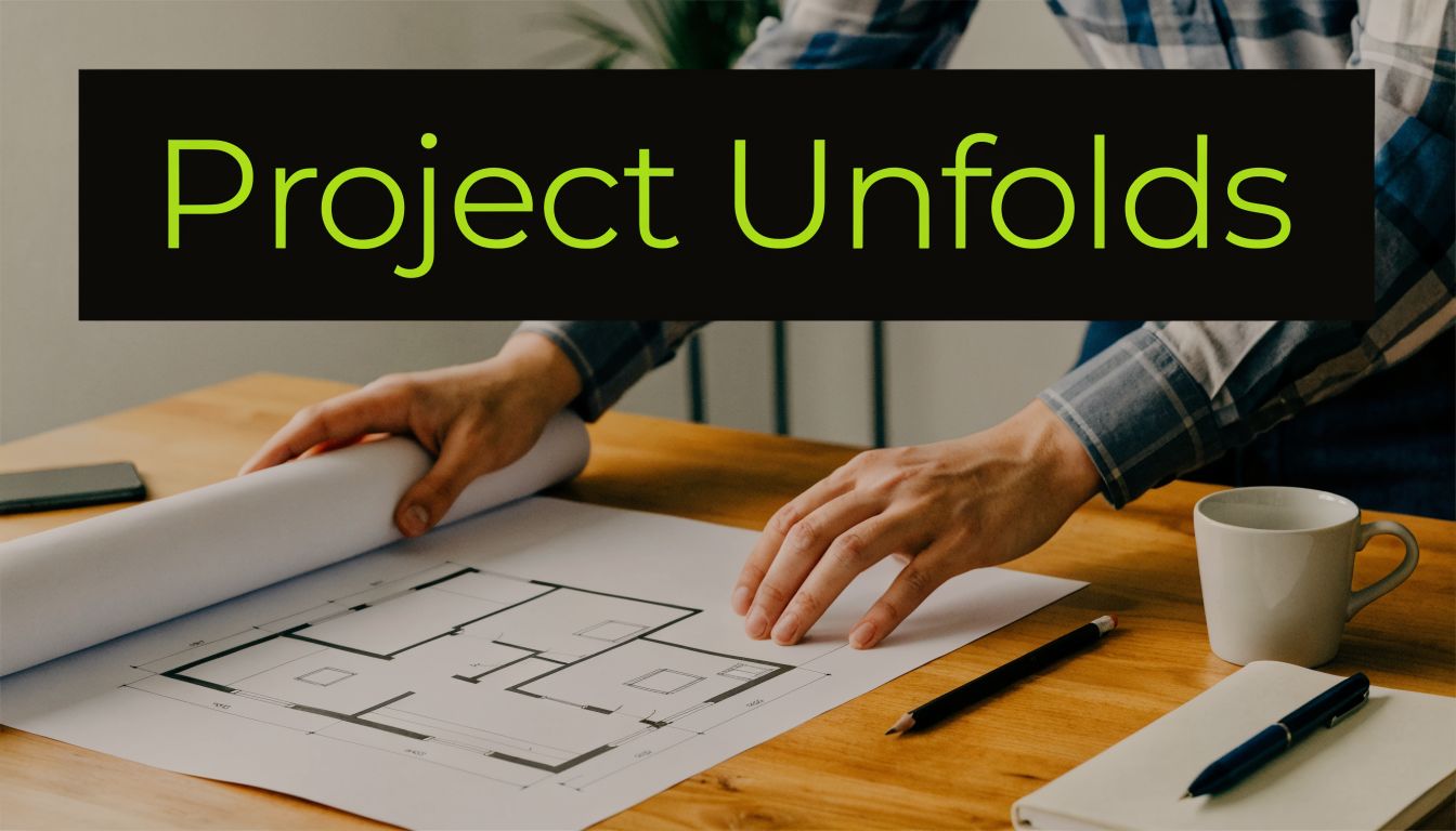 A person unrolling architectural blueprints on a wooden desk with a coffee mug, pencil, and notebook.