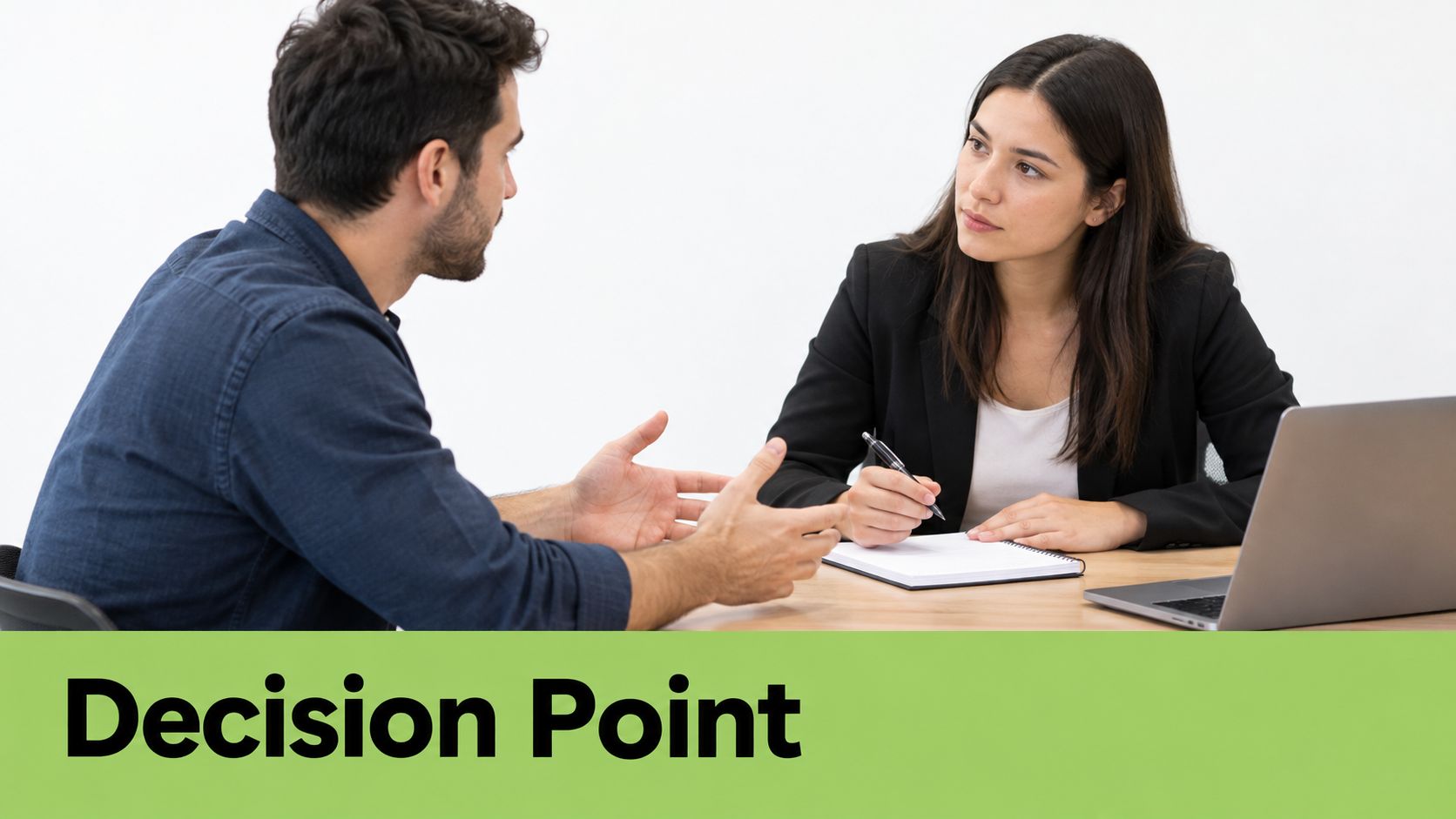 A professional woman in a business suit takes notes during an interview with a man in an office.