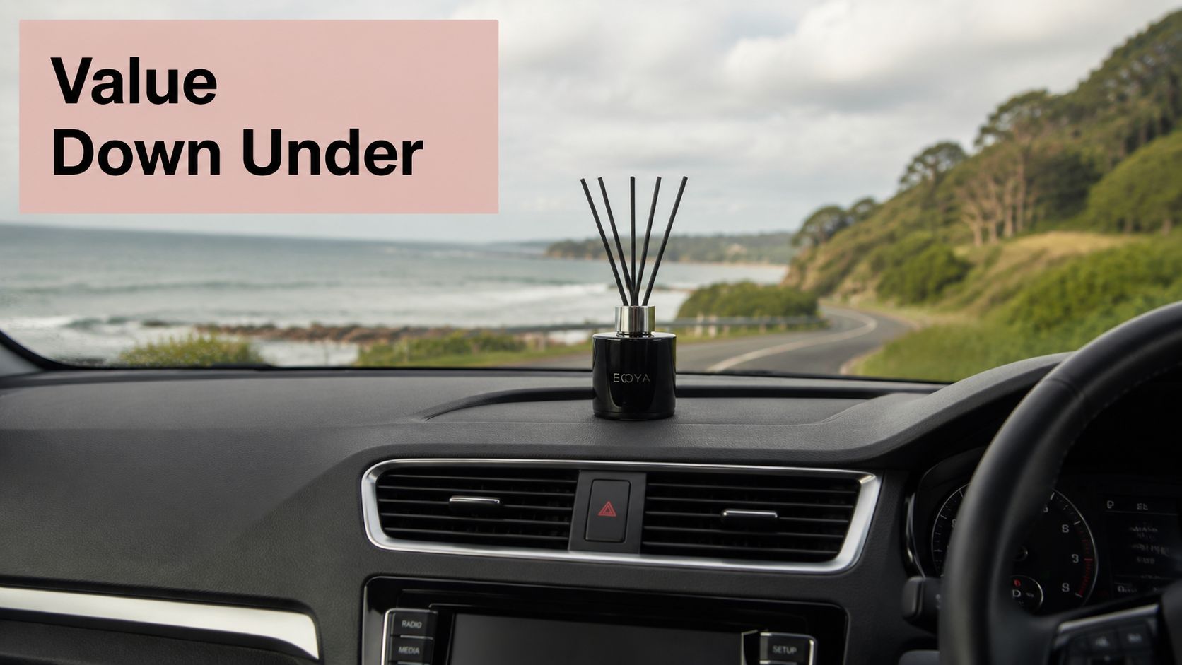 An ECOYA car diffuser with black reeds placed on the dashboard of a car overlooking a coastal road.