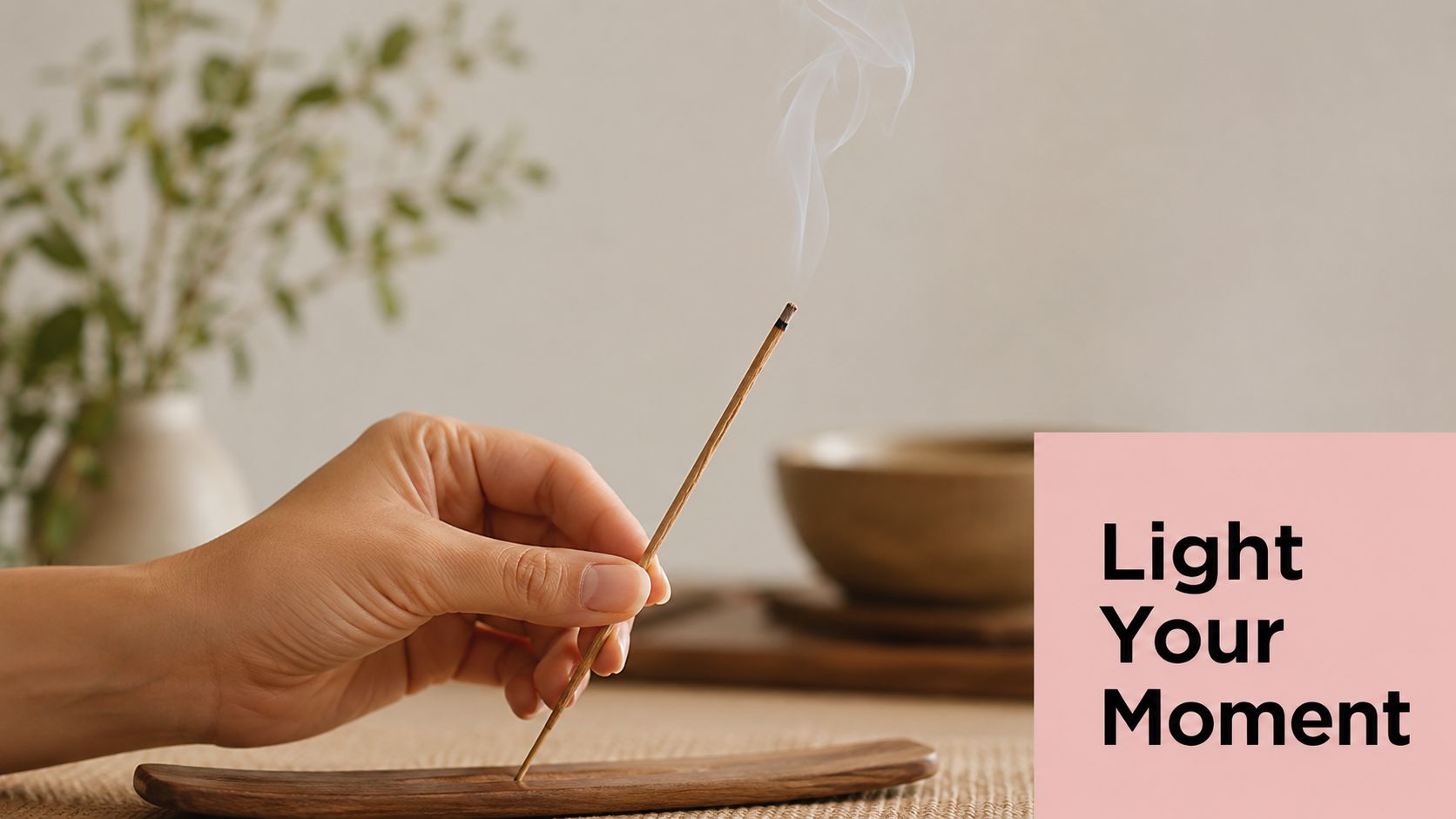 A hand holding a smoldering incense stick over a wooden holder on a textured surface.