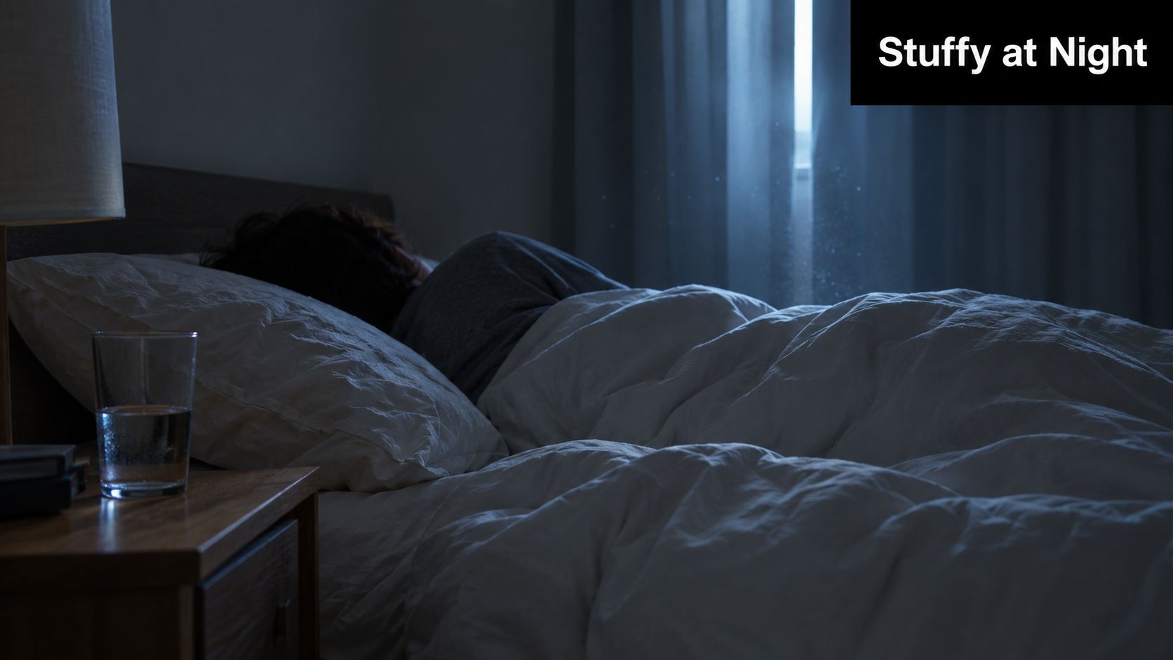 A person sleeping in a dark bedroom at night with air particles visible near the window light.