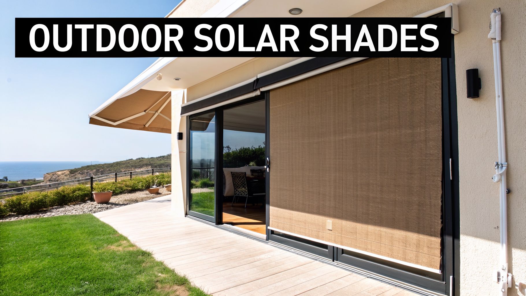 A modern patio with a brown outdoor solar shade on a sliding glass door, overlooking the ocean.